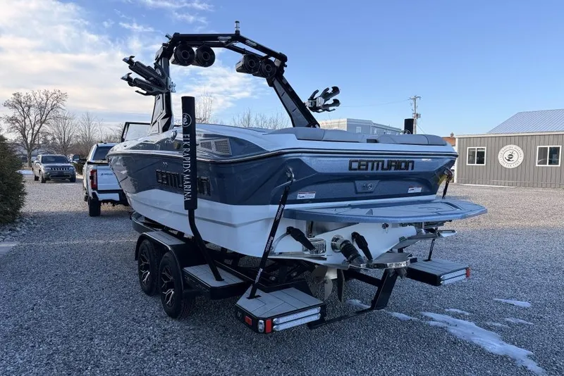 Slide: The Image of 2026 Centurion Nv233 boat on trailer, parked outdoors near a marina. - 5