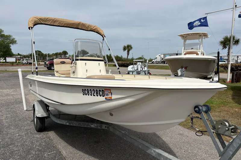 Slide: The Image of 2011 Scout 160 Sportfish boat on trailer, featuring a beige canopy and sleek design. - 5