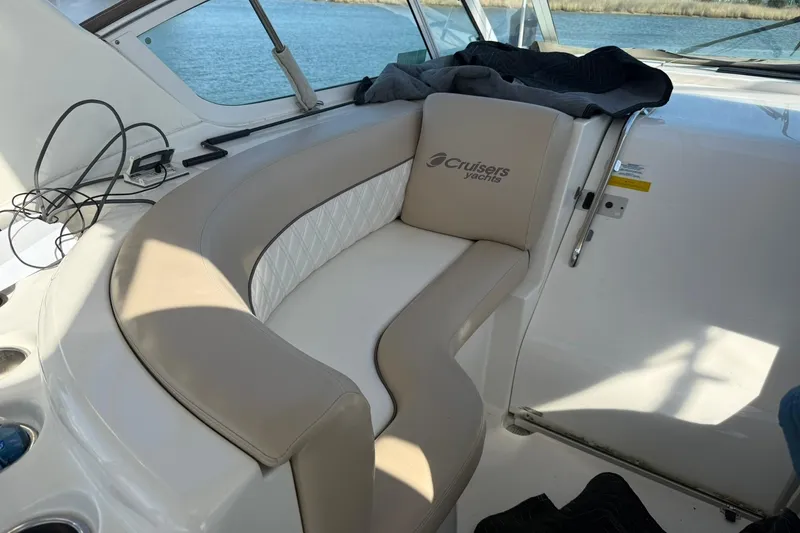 Slide: The Image of 2001 Cruisers Yachts 4450 Express Motoryacht interior seating with logo, overlooking water. - 7