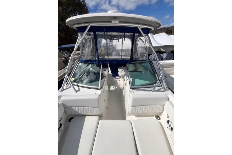 Slide: The Image of 2014 Robalo R247 Dual Console boat with white seating and blue canopy. - 14