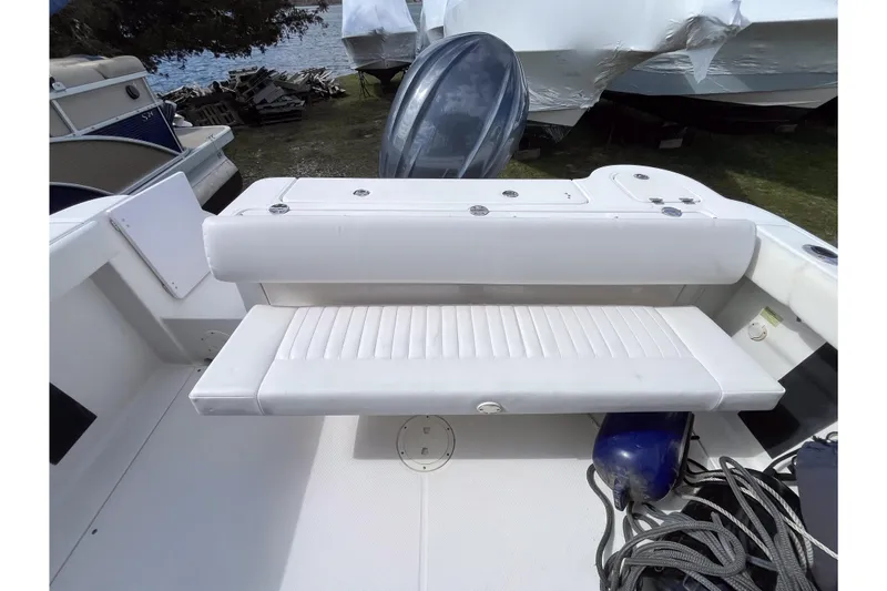 Slide: The Image of 2014 Robalo R247 Dual Console boat with white seating and storage area. - 3