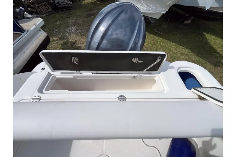 Slide: The Image of 2014 Robalo R247 Dual Console boat with open storage compartment and visible outboard motor. - 4