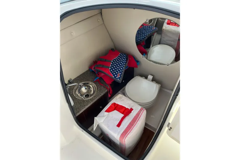 Slide: The Image of 2014 Robalo R247 Dual Console boat interior with sink, toilet, and life jackets. - 8