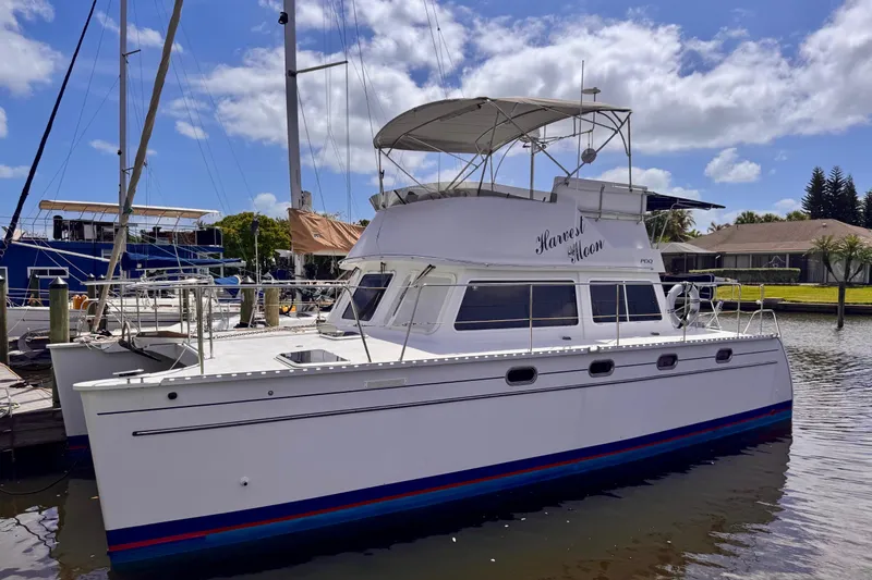 The Image of 2006 PDQ PowerCat boat docked in a marina under a partly cloudy sky. - 1