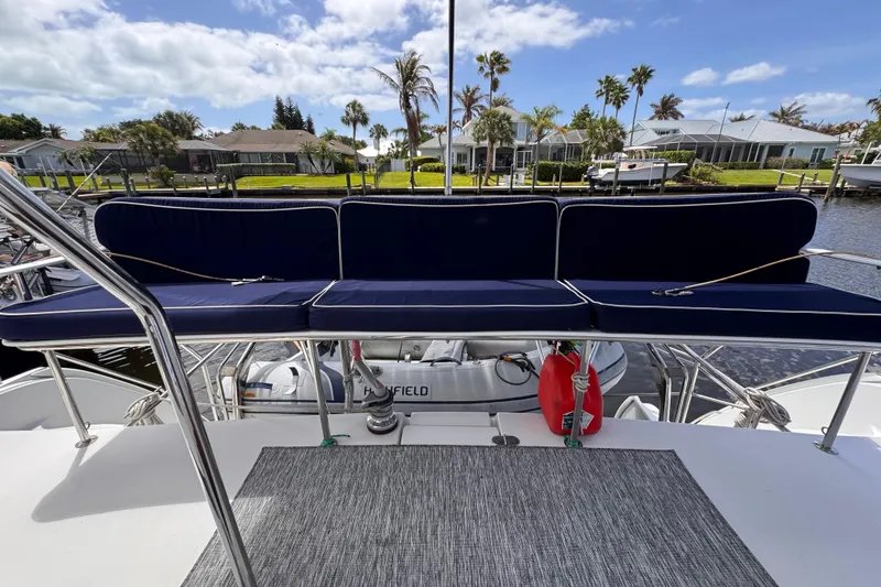 Slide: The Image of 2006 PDQ PowerCat boat with blue seating, docked near waterfront homes under a clear sky. - 22