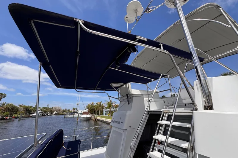 Slide: The Image of 2006 PDQ PowerCat boat with blue canopy, docked by a scenic waterfront. - 25