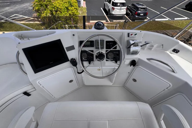 Slide: The Image of 2006 PDQ PowerCat helm with steering wheel, controls, and navigation screen in a marina setting. - 27
