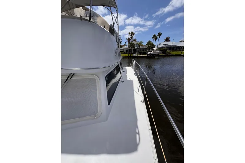 Slide: The Image of 2006 PDQ PowerCat boat docked by a scenic waterfront with palm trees. - 35