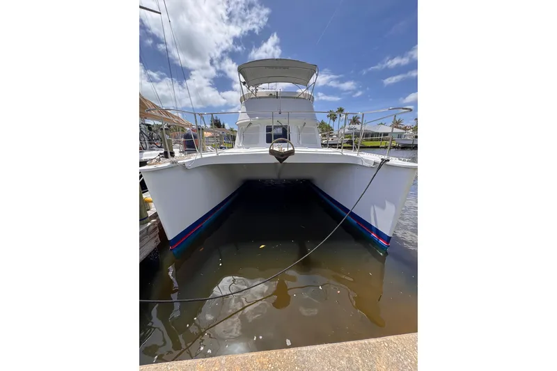Slide: The Image of Front view of a 2006 PDQ PowerCat boat docked in a marina under a sunny sky. - 36