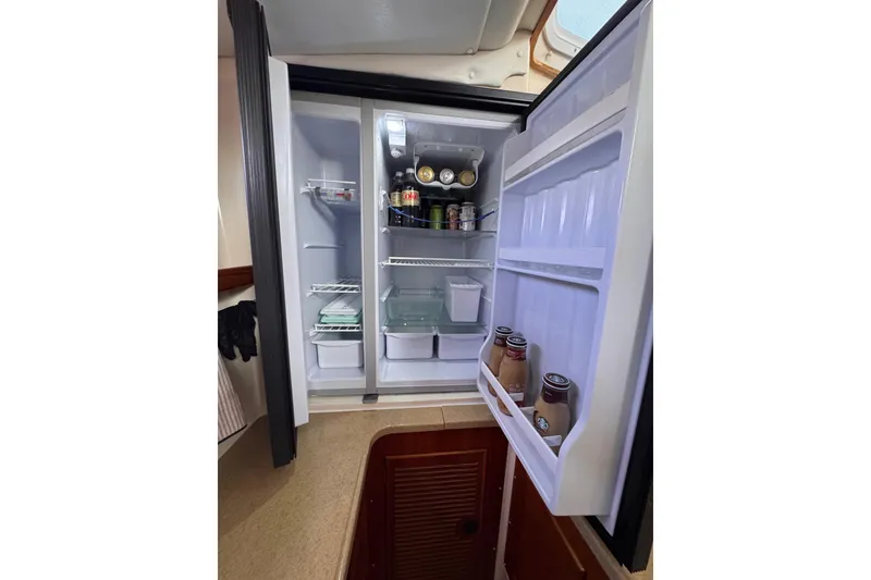 Slide: The Image of Open refrigerator inside 2006 PDQ PowerCat boat, stocked with beverages and food items. - 6