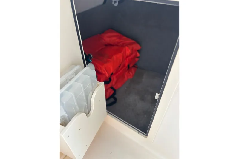 Slide: The Image of Storage compartment on 2022 Grady-White Freedom 235 boat with red life jackets. - 17