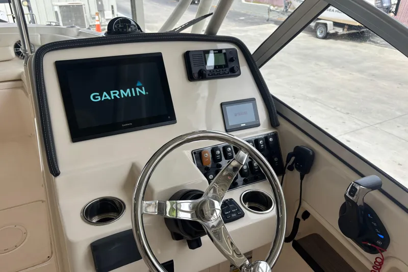 Slide: The Image of Helm of 2022 Grady-White Freedom 235 with Garmin navigation system and steering wheel. - 22