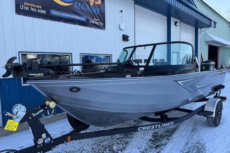 Slide: The Image of 2026 Crestliner 1650 Kodiak boat on trailer outside marine shop in snowy setting. - 2