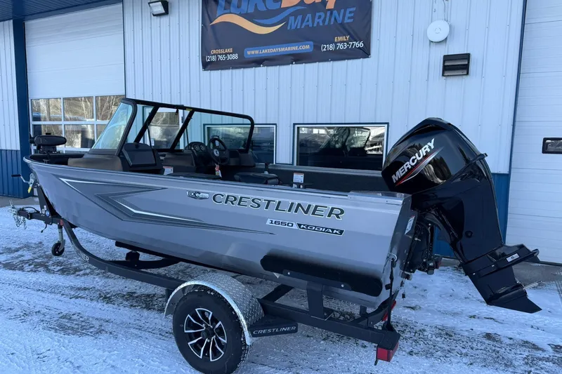 Slide: The Image of 2026 Crestliner 1650 Kodiak boat with Mercury engine on trailer, parked outside marine shop. - 3
