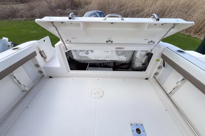 Slide: The Image of 2020 Robalo R247 Dual Console boat with open storage compartment, showcasing spacious deck design. - 4