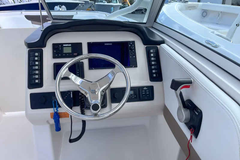Slide: The Image of 2020 Robalo R247 Dual Console boat dashboard with steering wheel and navigation controls. - 6