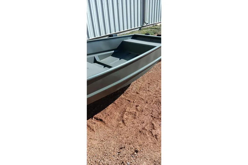 Slide: The Image of 2026 Tracker Topper 1542 LW Riveted Jon boat on gravel near metal fence. - 6