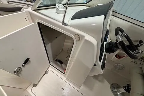 Slide: The Image of 2022 Sailfish 245 DC boat interior with open storage compartment and steering wheel. - 10