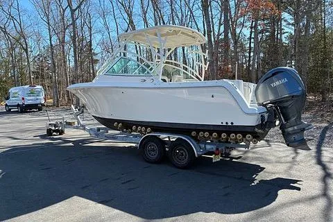 Slide: The Image of 2022 Sailfish 245 DC boat on trailer with Yamaha outboard motor in a wooded area. - 2