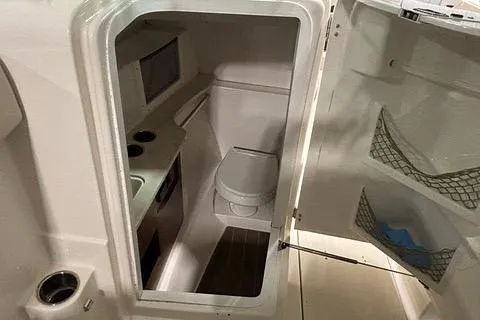 Slide: The Image of 2022 Sailfish 245 DC boat interior with compact bathroom and storage features. - 7