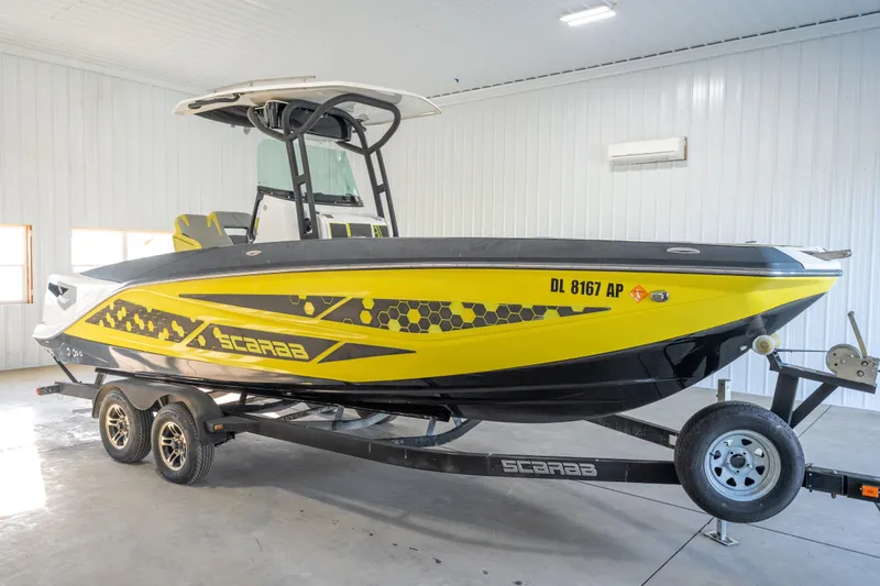 The Image of 2022 Scarab 255 Open ID boat in a garage, yellow and black design on trailer. - 0