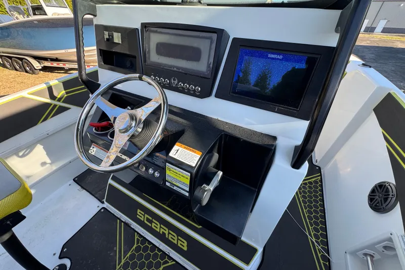 Slide: The Image of 2022 Scarab 255 Open ID boat dashboard with steering wheel and navigation screens. - 5