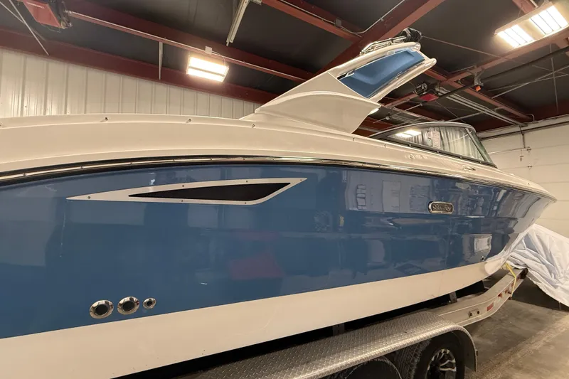 The Image of 2026 Sea Ray SDX 270 boat in a garage, featuring a sleek blue and white design. - 1