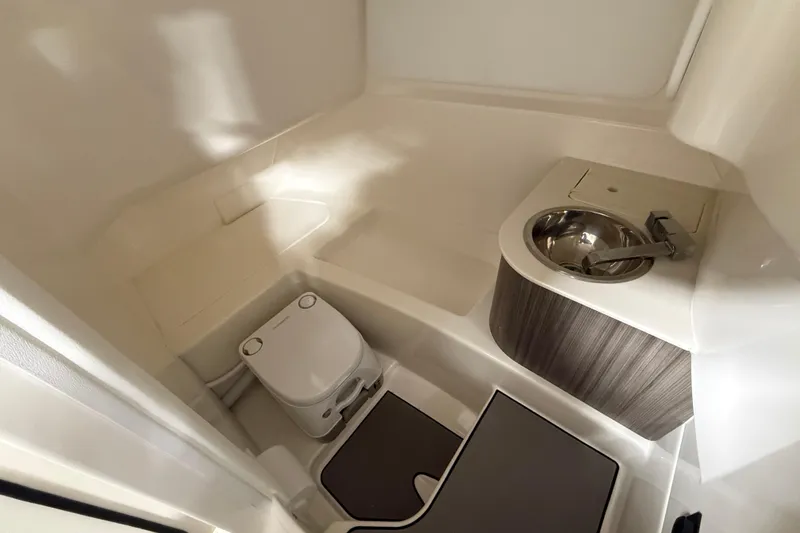 Slide: The Image of 2026 Sea Ray SDX 270 boat bathroom with compact toilet and stainless steel sink. - 21