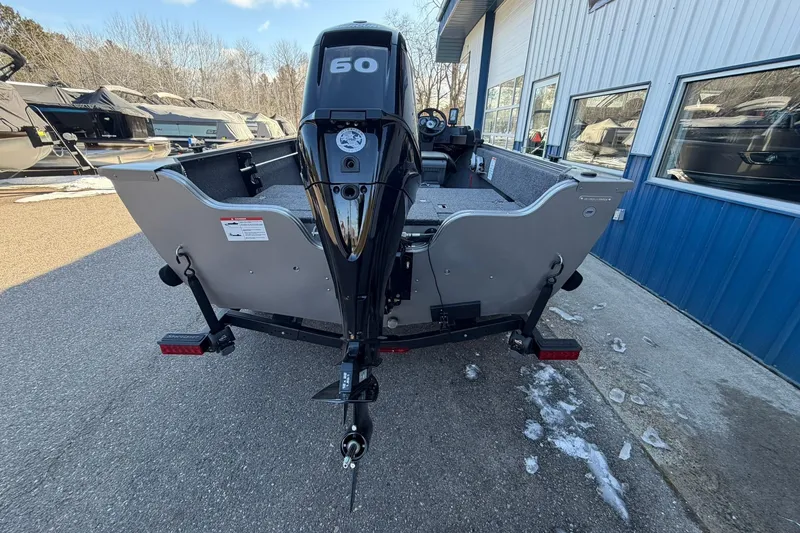 Slide: The Image of 2026 Crestliner 1650 Kodiak boat with 60 HP motor, parked outside a blue building. - 3