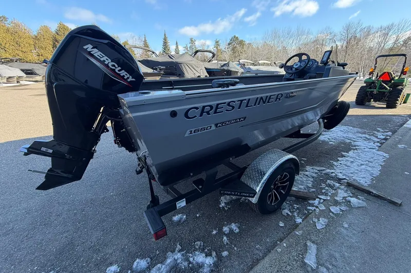 Slide: The Image of 2026 Crestliner 1650 Kodiak boat with Mercury engine on trailer, parked outdoors. - 4