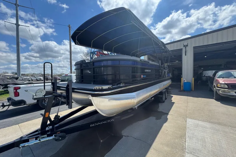 Slide: The Image of 2020 Bennington R 25 RFB pontoon boat on trailer, parked outside a garage. - 6