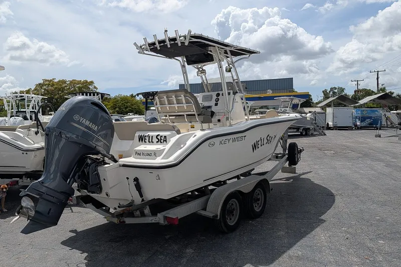 Slide: The Image of 2022 Key West 219 FS boat on trailer with Yamaha engine, parked outdoors. - 2