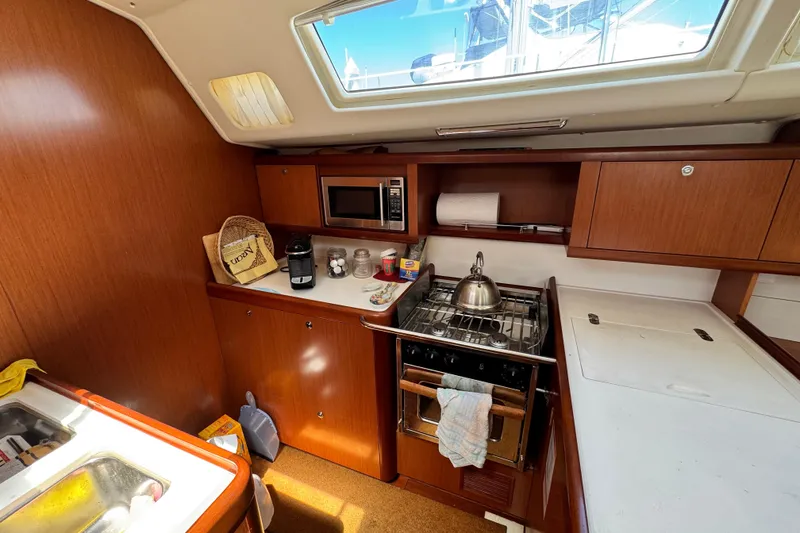 Slide: The Image of Interior of 2008 Beneteau 49 yacht kitchen with stove, microwave, and wooden cabinetry. - 38