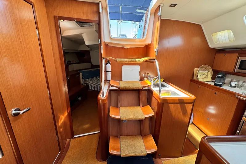 Slide: The Image of Interior of a 2008 Beneteau 49 yacht featuring wooden cabinetry and a compact kitchen area. - 40
