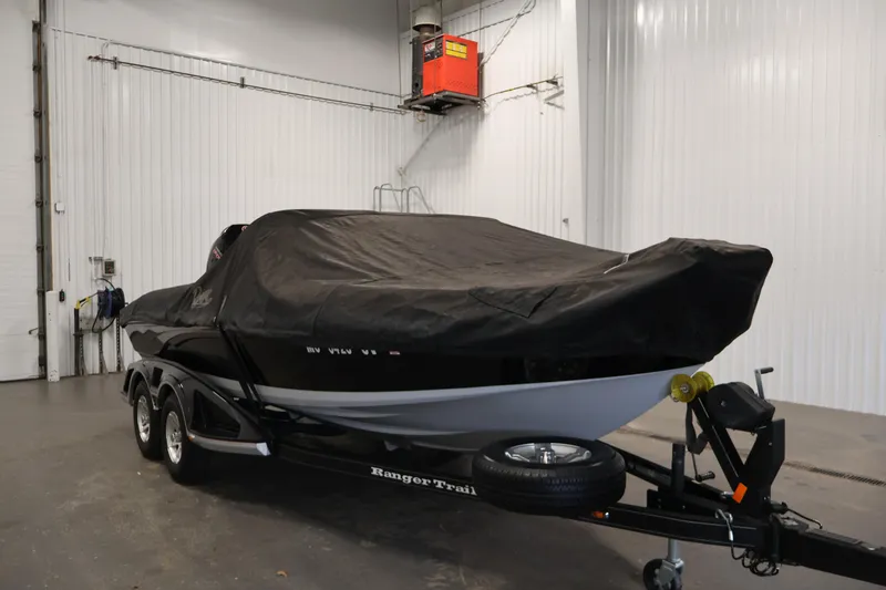 Slide: The Image of 2022 Ranger 1880MS boat covered in black tarp, parked indoors on trailer. - 49