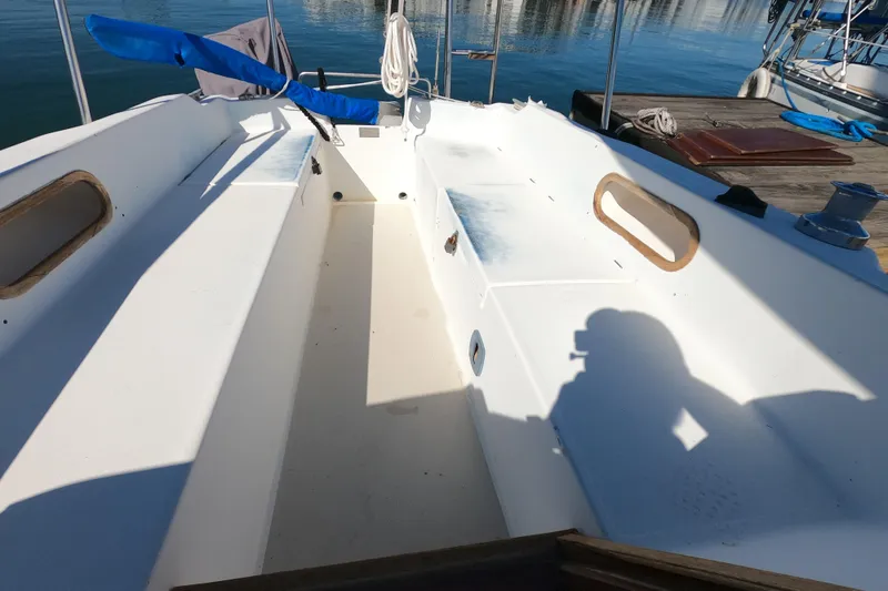 Slide: The Image of 1983 Catalina 25 sailboat cockpit with white seating and blue cover, docked at marina. - 16