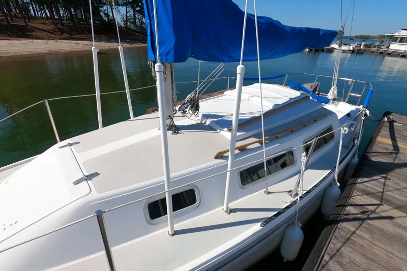 Slide: The Image of 1983 Catalina 25 sailboat docked with blue sail cover, calm waters in background. - 19