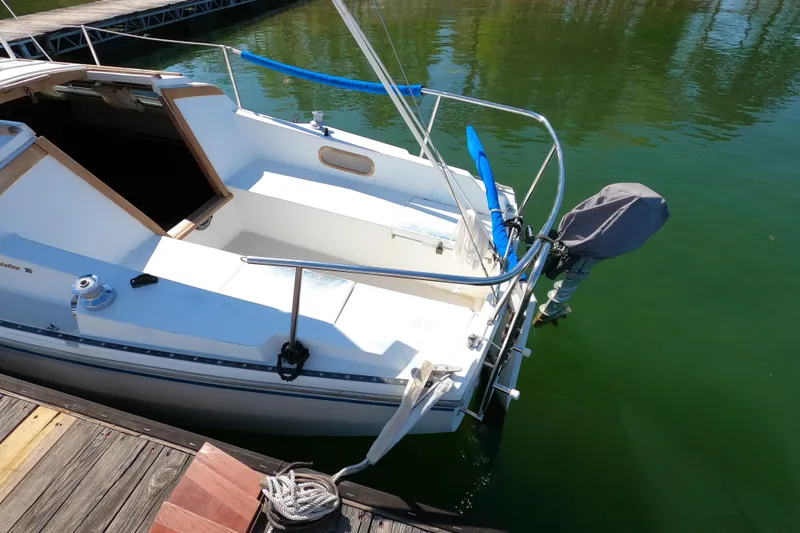 Slide: The Image of 1983 Catalina 25 sailboat docked, featuring a covered outboard motor and open cockpit. - 5