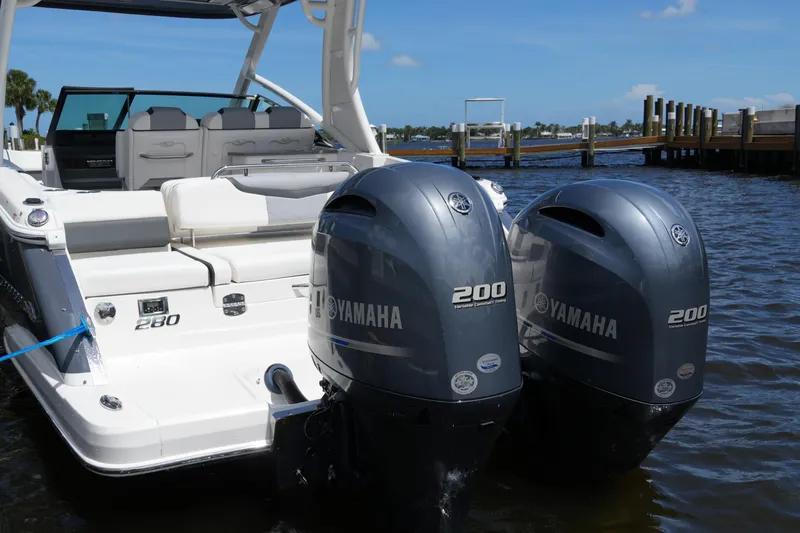 Slide: The Image of 2022 Chaparral 280 OSX boat with twin Yamaha 200 engines docked by the water. - 24