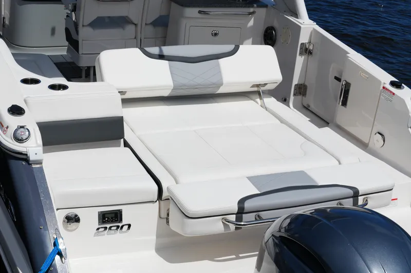 Slide: The Image of 2022 Chaparral 280 OSX boat interior with white seating and cup holders by the water. - 40