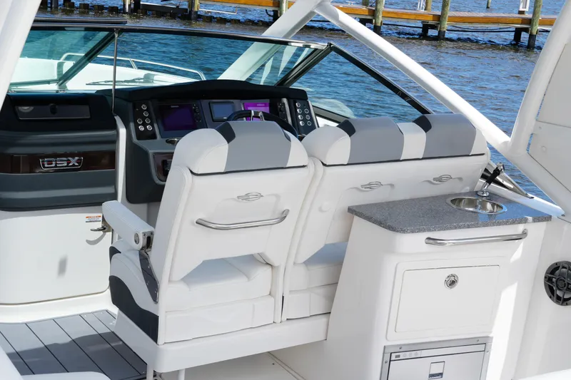 Slide: The Image of 2022 Chaparral 280 OSX boat interior with helm, seating, and kitchenette by the water. - 41