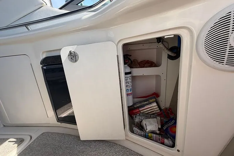 Slide: The Image of Open storage compartment on 2007 Sea Ray 300 Sundancer boat, containing fire extinguisher and supplies. - 13
