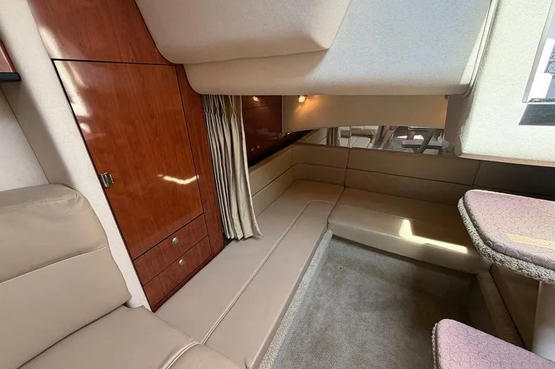 Slide: The Image of Interior of 2007 Sea Ray 300 Sundancer, featuring beige seating and wooden cabinetry. - 27
