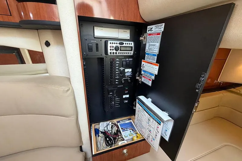 Slide: The Image of Electrical panel inside 2007 Sea Ray 300 Sundancer boat cabin, featuring controls and manuals. - 28