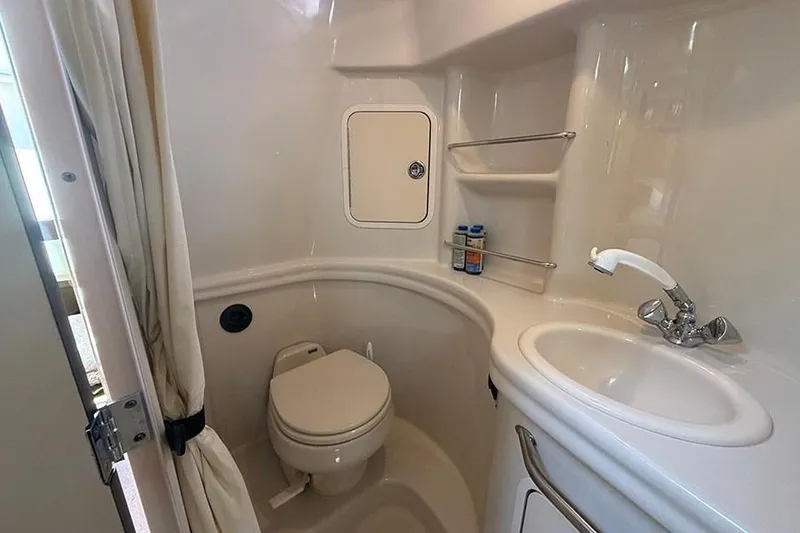 Slide: The Image of 2007 Sea Ray 300 Sundancer bathroom with toilet, sink, and storage shelves. - 38
