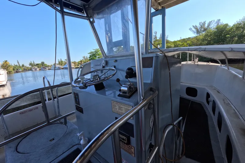 Slide: The Image of 1979 Willard Marine 50 Utility Launch interior with steering wheel and controls, docked by a scenic river. - 16