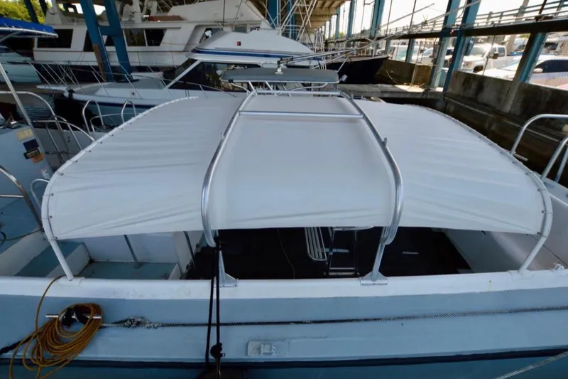 Slide: The Image of 1979 Willard Marine 50 Utility Launch with white canopy docked in a marina. - 20