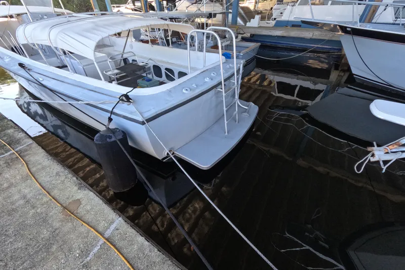 Slide: The Image of 1979 Willard Marine 50 Utility Launch docked at marina, featuring white canopy and metal ladder. - 29