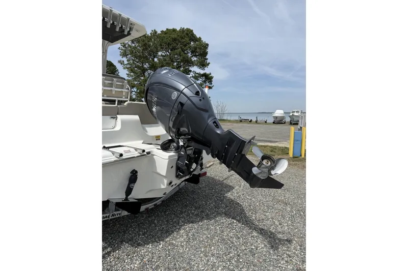 Slide: The Image of 2026 Key West 219 FS boat with powerful outboard motor, parked on gravel near water. - 5