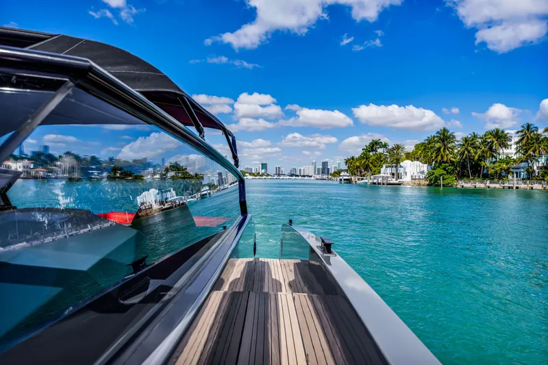 Slide: The Image of Vanquish Yachts 45 (2021) cruising on turquoise waters with city skyline and palm trees. - 49